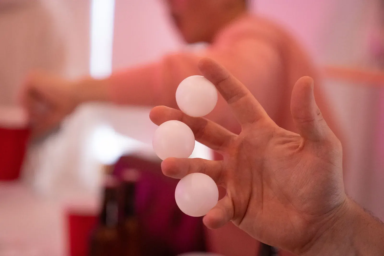 Mano sujetando tres pelotas de tenis de mesa